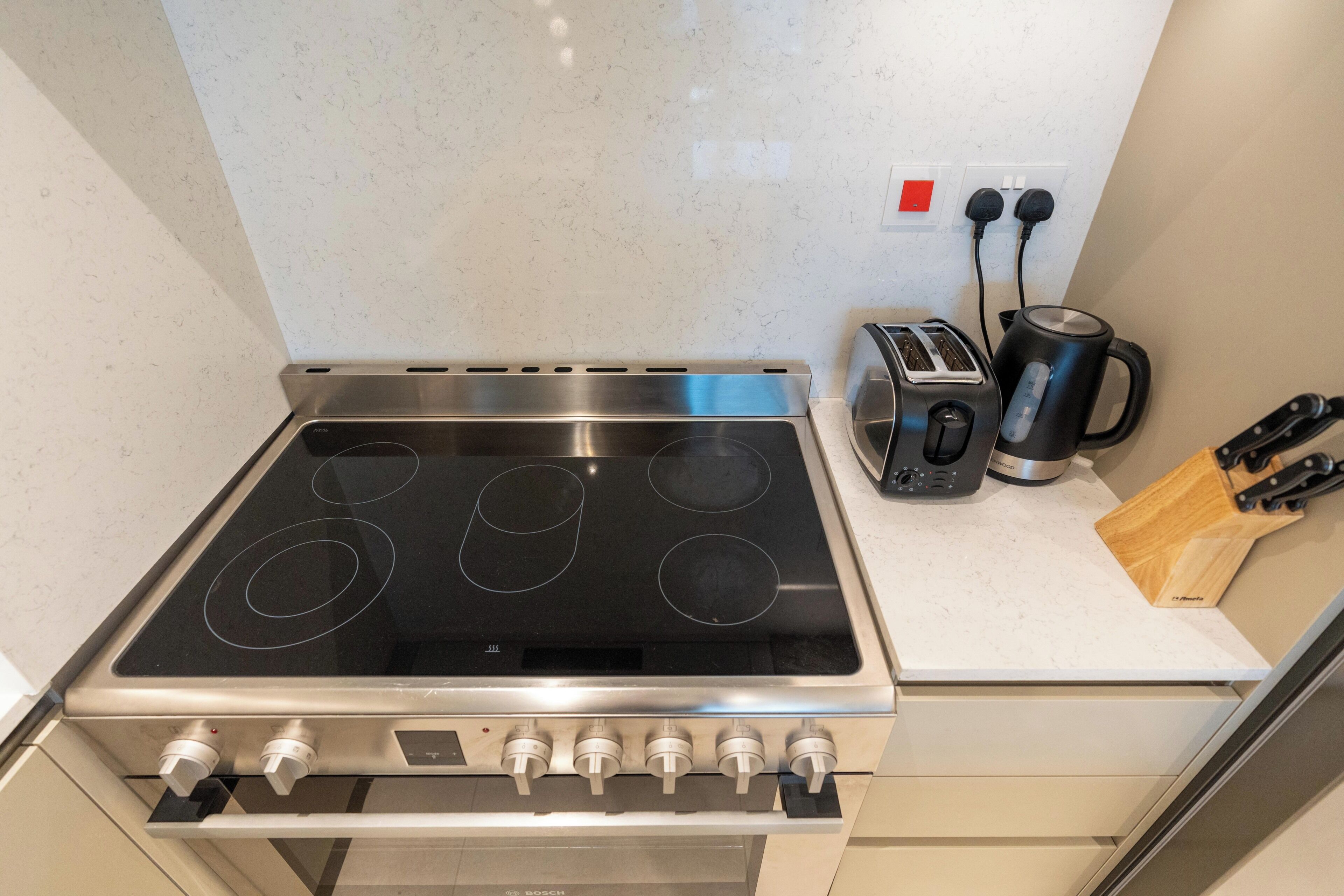 Una cocina con estufa a gas Bosch, un tostador y una cafetera sobre la encimera.