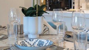 A dining table set with plates, glasses, and a potted orchid. - bnbme - Al Jazi - 2BR (Dubai)