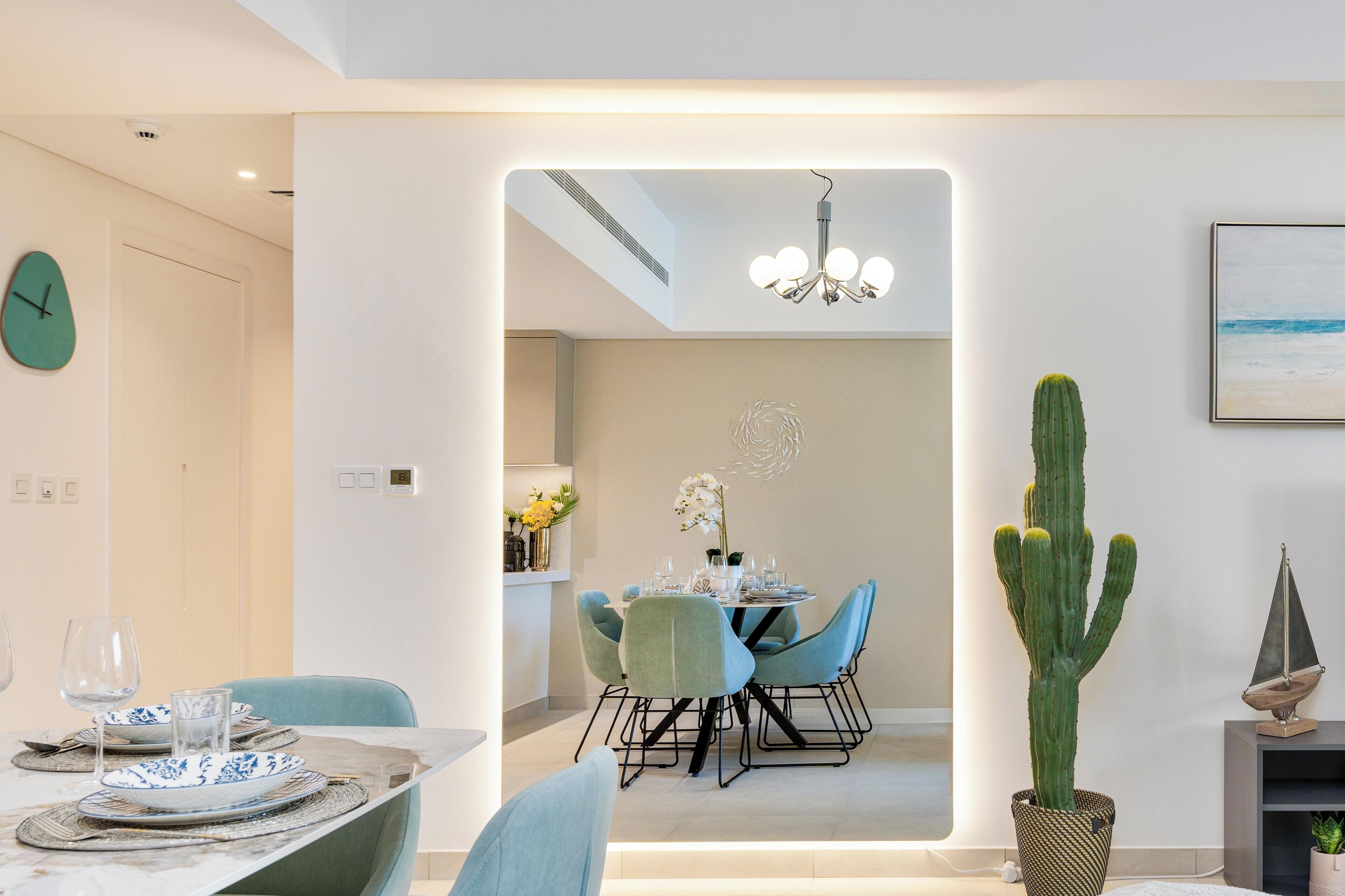 A modern dining area with a table set for two, chairs, and a cactus plant.
