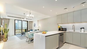 A modern kitchen with a central island, built-in appliances, and a dining area with a view. - bnbme - Al Jazi - 2BR (Dubai)