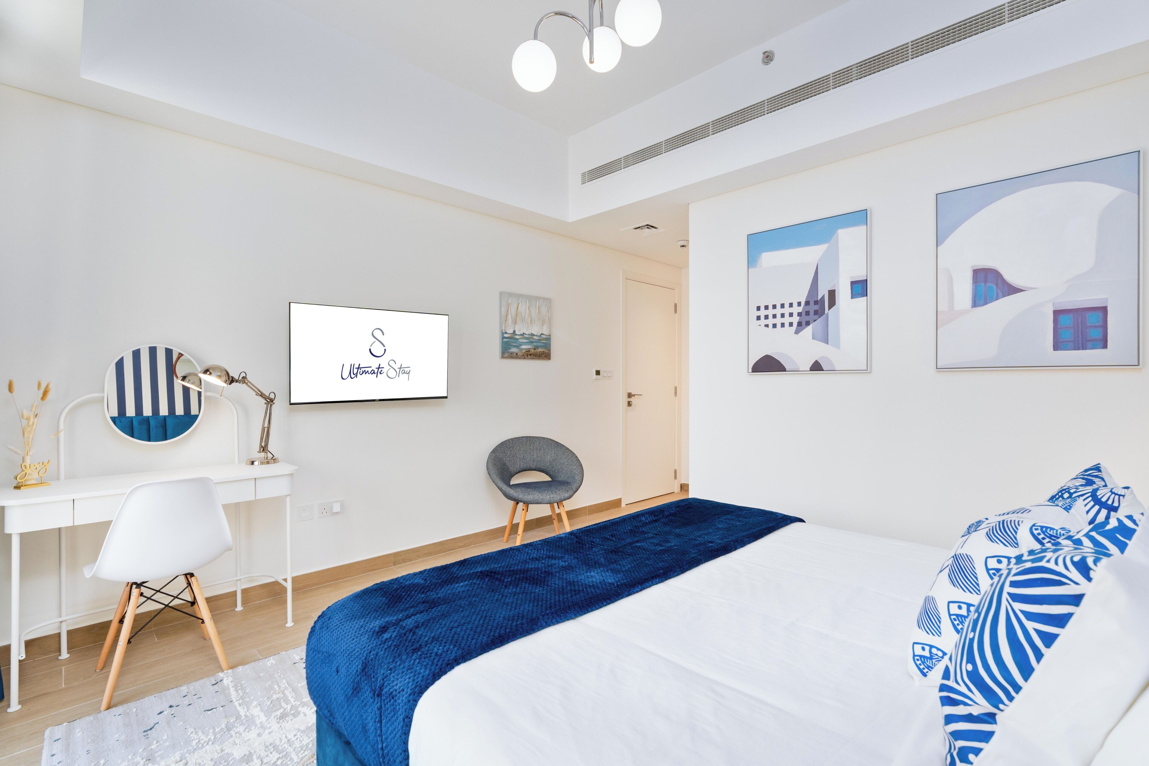 A modern bedroom with a bed, desk, chair, and artwork on the walls.