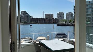 A balcony with a view of a river and buildings across it.