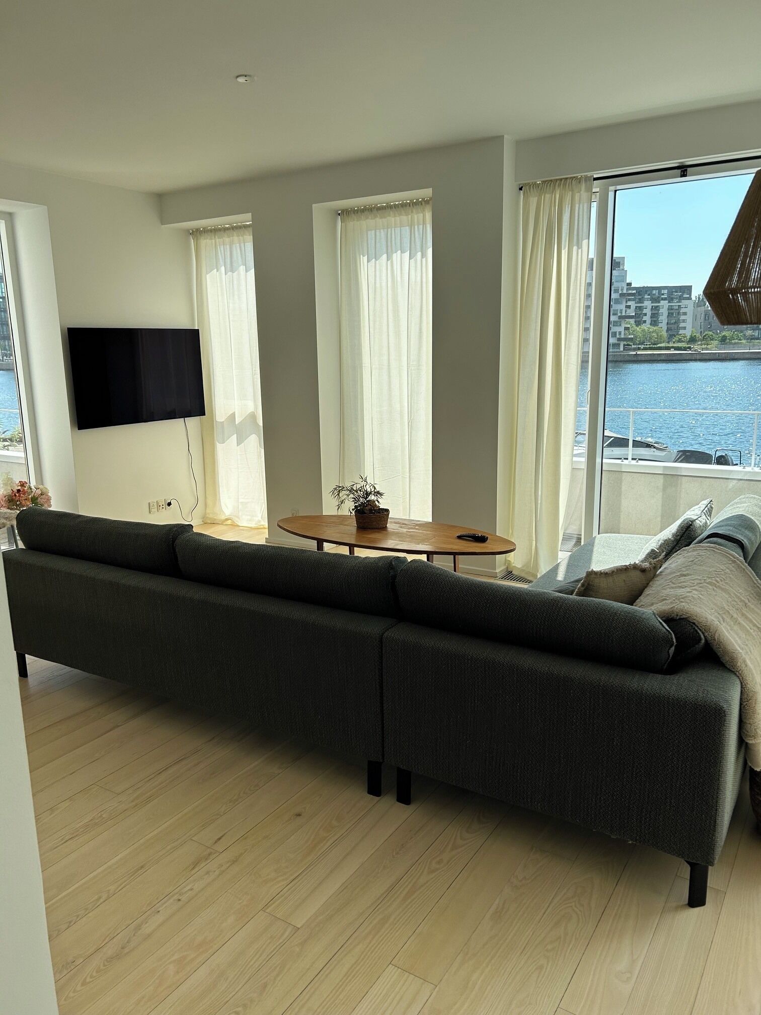 A modern living room with a large sofa, a flat-screen TV, and a dining table.