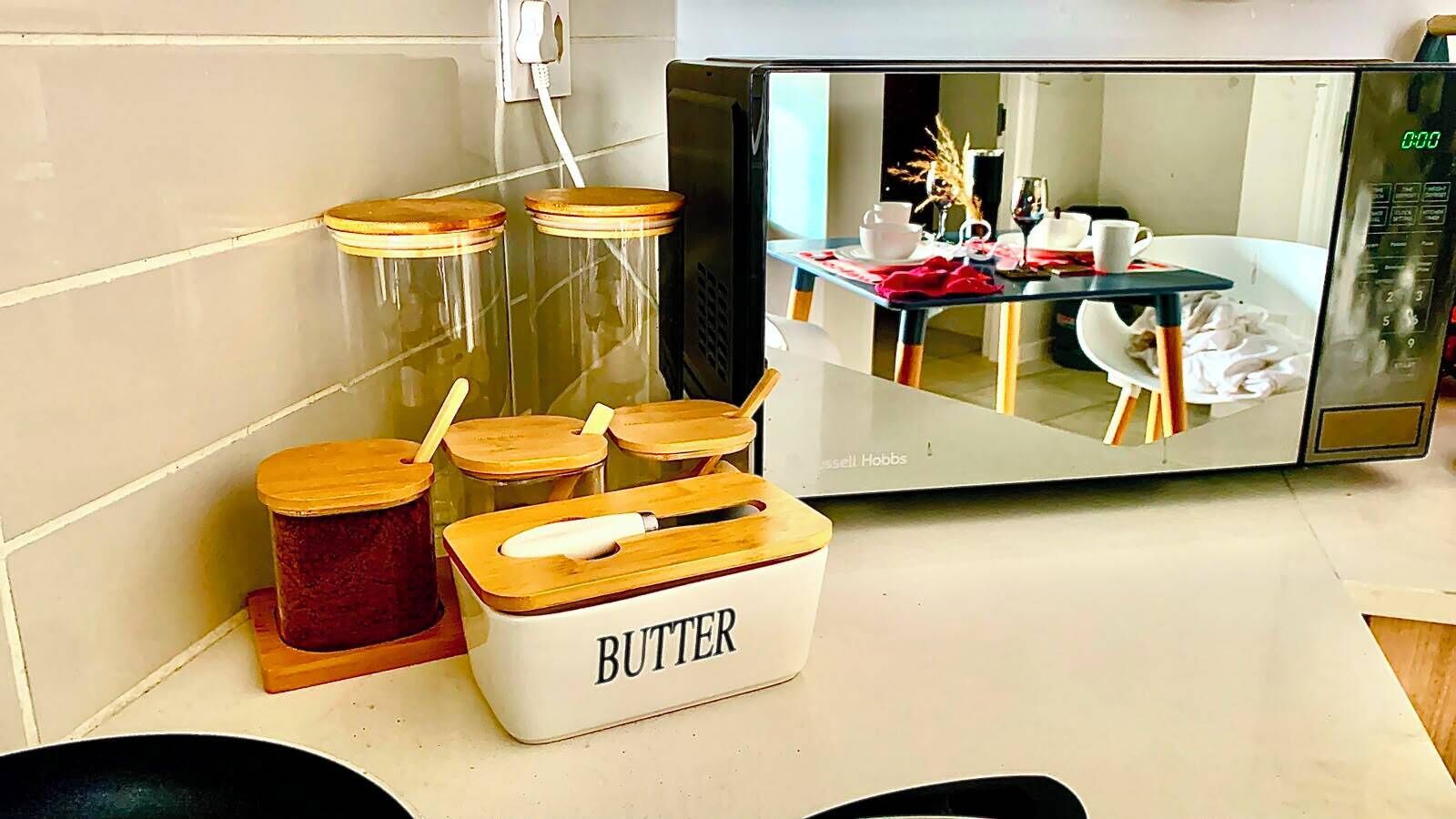 Un plan de travail de cuisine avec un récipient à beurre, des bocaux et un four à micro-ondes.