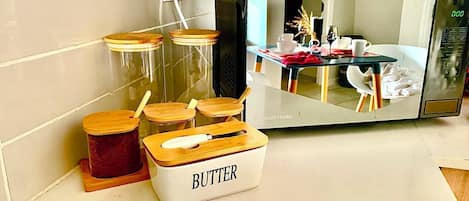 A kitchen counter with a butter container, jars, and a microwave.