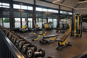 A gym with weightlifting equipment, benches, and dumbbells.