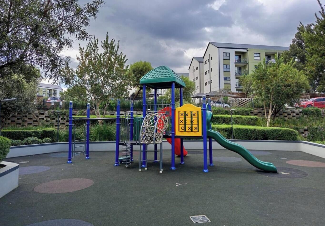 A playground with a climbing structure, a slide, and a fenced area.