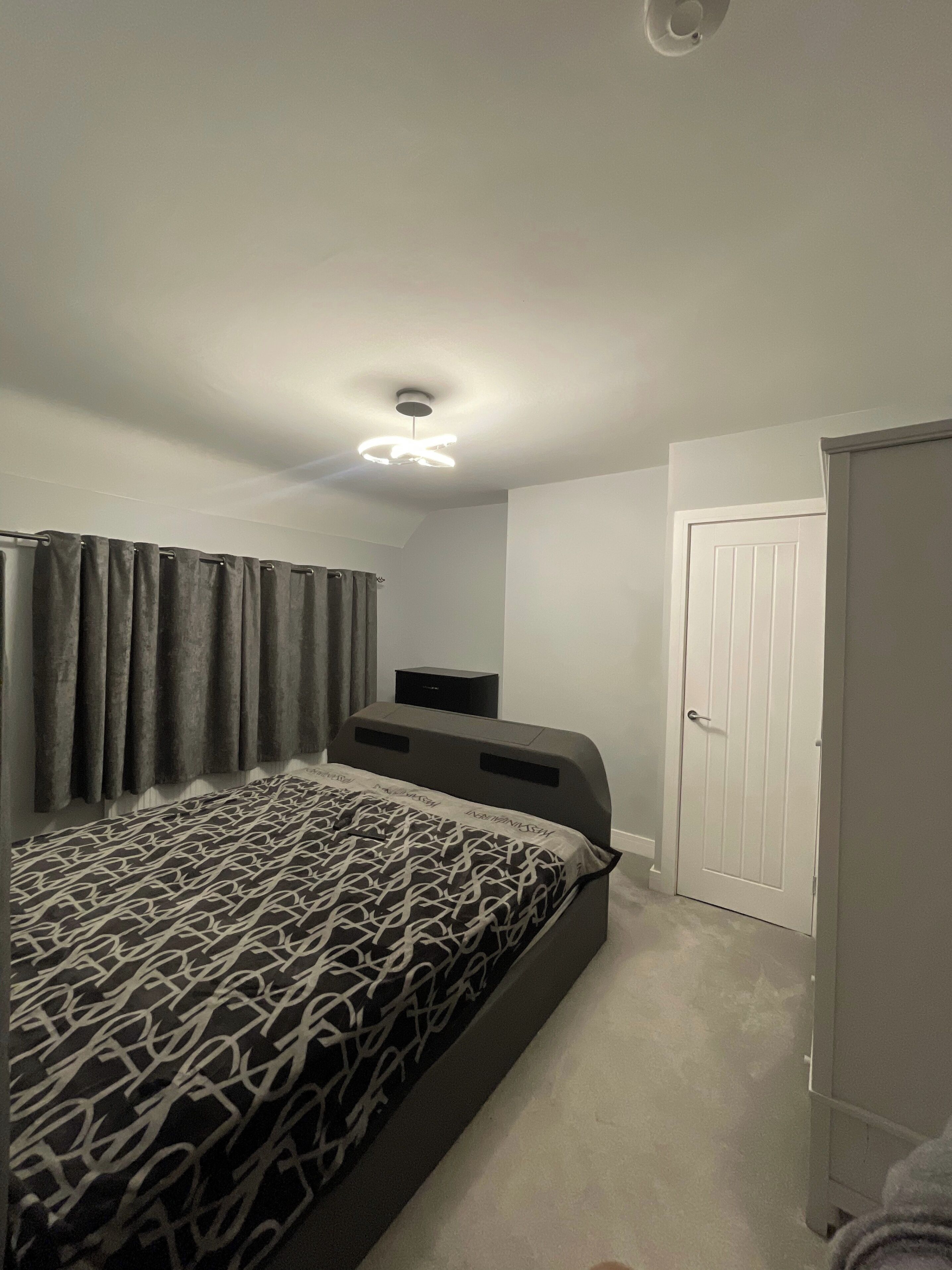 Een slaapkamer met een bed, een plafondventilator, een kledingkast en een deur.
