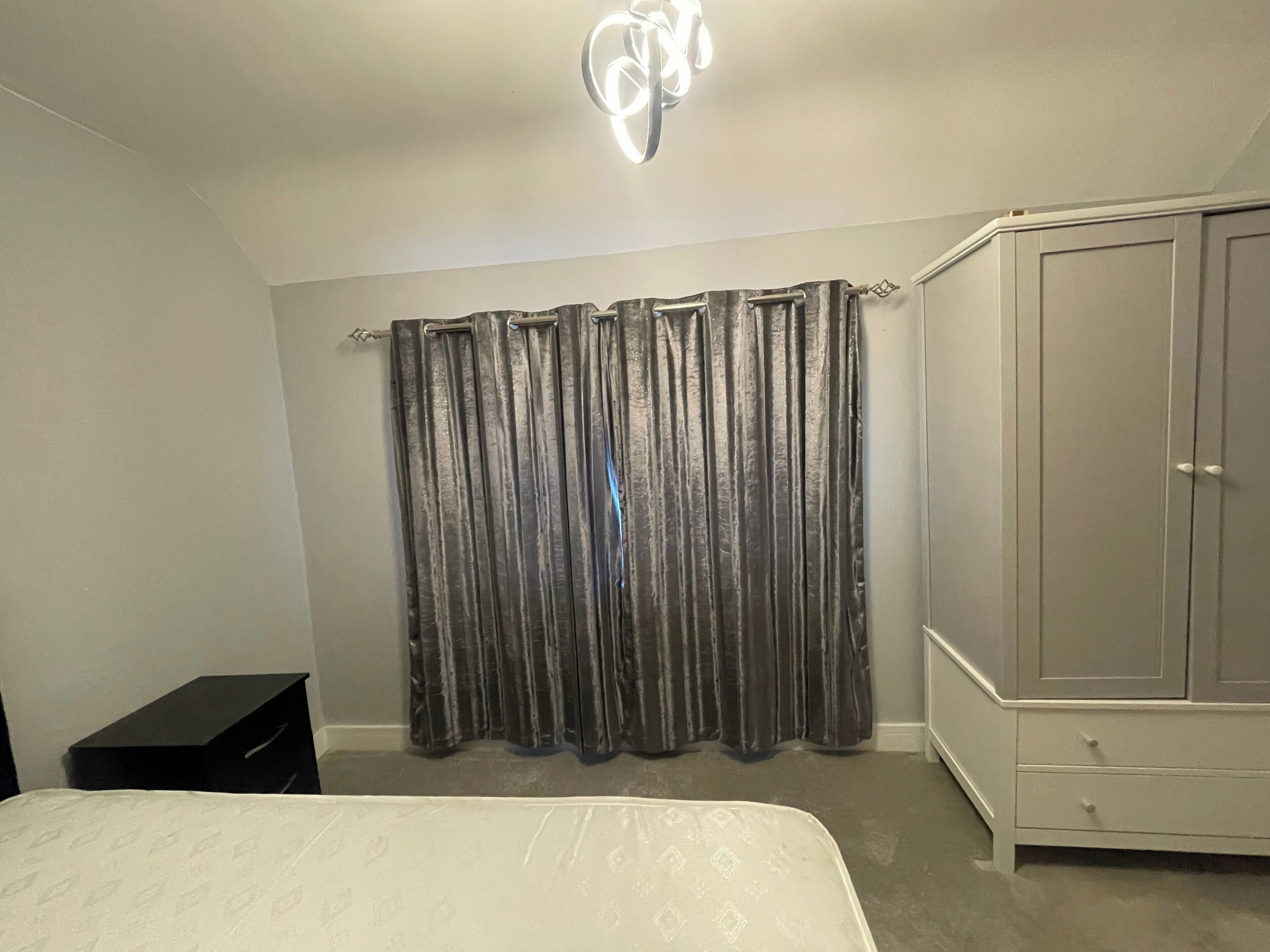 Ein Schlafzimmer mit Bett, Kleiderschrank und Vorhang.