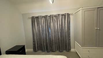 Ein Schlafzimmer mit Bett, Kleiderschrank und Vorhang.