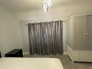A bedroom with a bed, a wardrobe, and a curtain.