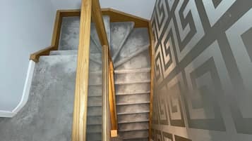 A wooden staircase with a geometric patterned wall.