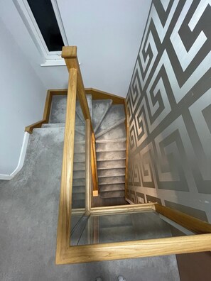 A wooden staircase with a geometric patterned wall.