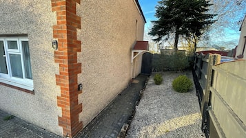 A residential building with a brick corner, a small garden with gravel, and a wooden fence.