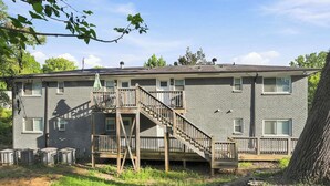 Ein zweistöckiges Gebäude mit einer Holzterrasse und einer Treppe zu einem Balkon.