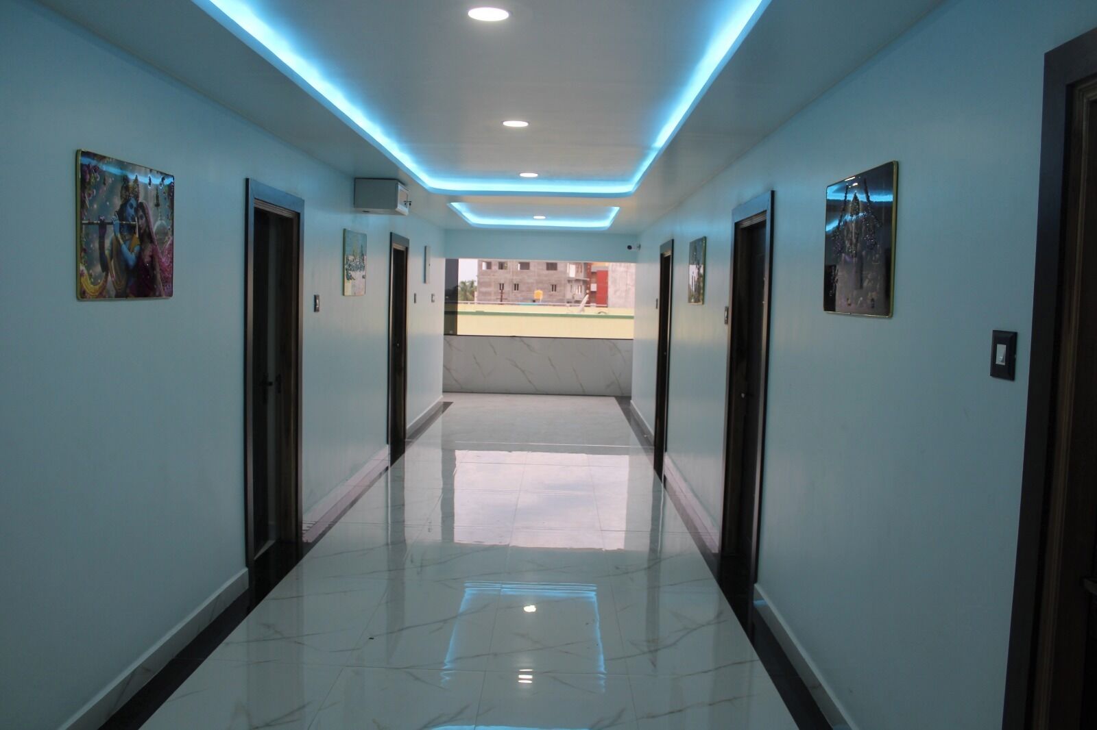 A hallway with a polished floor, recessed lighting, and framed artwork on the walls.