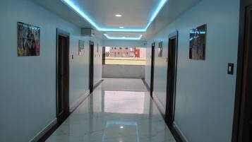 A hallway with a polished floor, recessed lighting, and framed artwork on the walls.