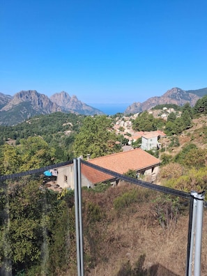 A mountainous landscape with a village and a view of the sea.