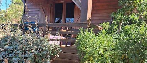 Una cabaña de madera con un porche y un pequeño jardín.
