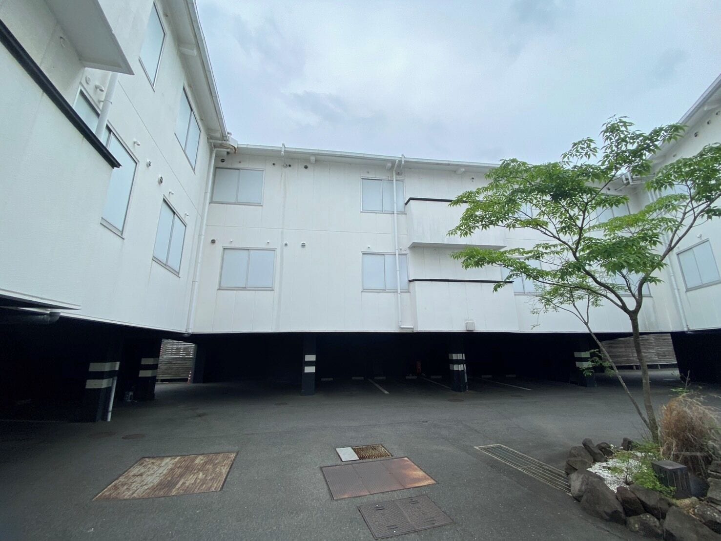 Une cour intérieure avec un bâtiment, un arbre et un espace de stationnement.