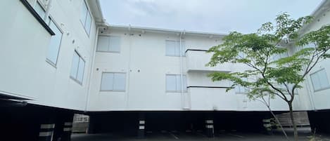 A courtyard with a building, a tree, and a parking area.