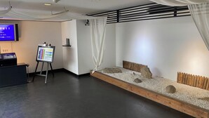 A room with a reception desk, a television, an information board, and a seating area with a decorative rock arrangement.