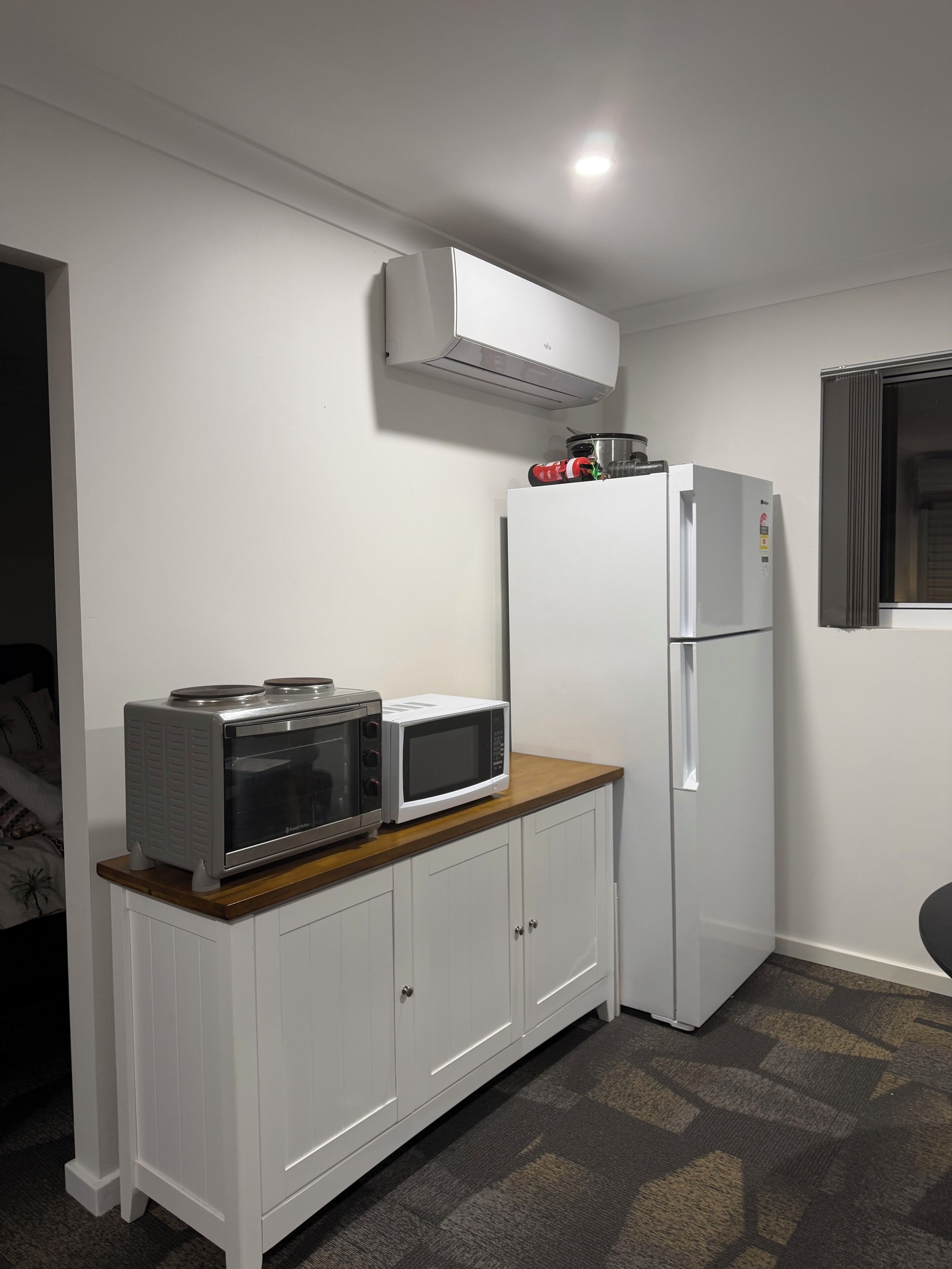 A compact kitchen with white cabinetry, a microwave, a toaster, and a refrigerator.