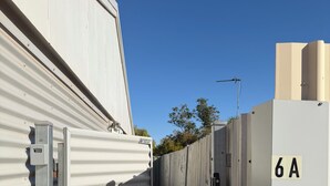 A corridor with portable metal structures, a security gate, and a utility box labeled '6A'.