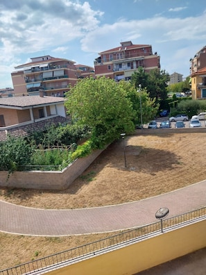 A residential area with multiple apartment buildings, a paved walkway, and a landscaped garden area. - 
Feel right at home and relax just steps from the sea. (Pescara)