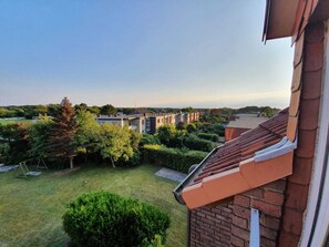 A residential area with a view of neighboring houses, a well-maintained lawn, and a brick building with a tiled roof. - Op'n Rugenbarg Vacation Rental Ebbe H60 (Cuxhaven)