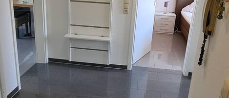 Ein Flur mit einem weißen Schrank, einem Bett und einem Schreibtisch mit einer Lampe.
