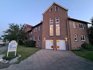 Ein zweistöckiges Backsteingebäude mit einer symmetrischen Fassade, großen Fenstern und einem zentralen Eingang.