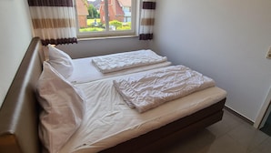 A bedroom with a bed, a bedside lamp, and a window with curtains. - Op'n Rugenbarg Vacation Rental Elbe H64 (Cuxhaven)