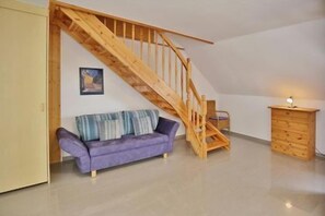 A room with a wooden staircase, a purple sofa, and a wooden cabinet. - "Sturmflut" Vacation Rental on the Rugenbarg (Cuxhaven)