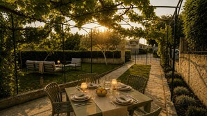 An outdoor dining area with a table set for two, surrounded by chairs, under a pergola with a view of a residential building. - Fortica Garden Apartment – Pula Arena, Free Parking (Pula)