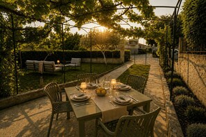An outdoor dining area with a table set for two, surrounded by chairs, under a pergola with a view of a residential building. - Fortica Garden Apartment – Pula Arena, Free Parking (Pula)
