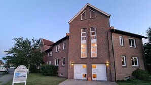 A two-story brick building with a symmetrical facade, large double doors, and a signboard in the foreground. - Op'n Rugenbarg Vacation Rental, Wadden Sea, H62 (Cuxhaven)