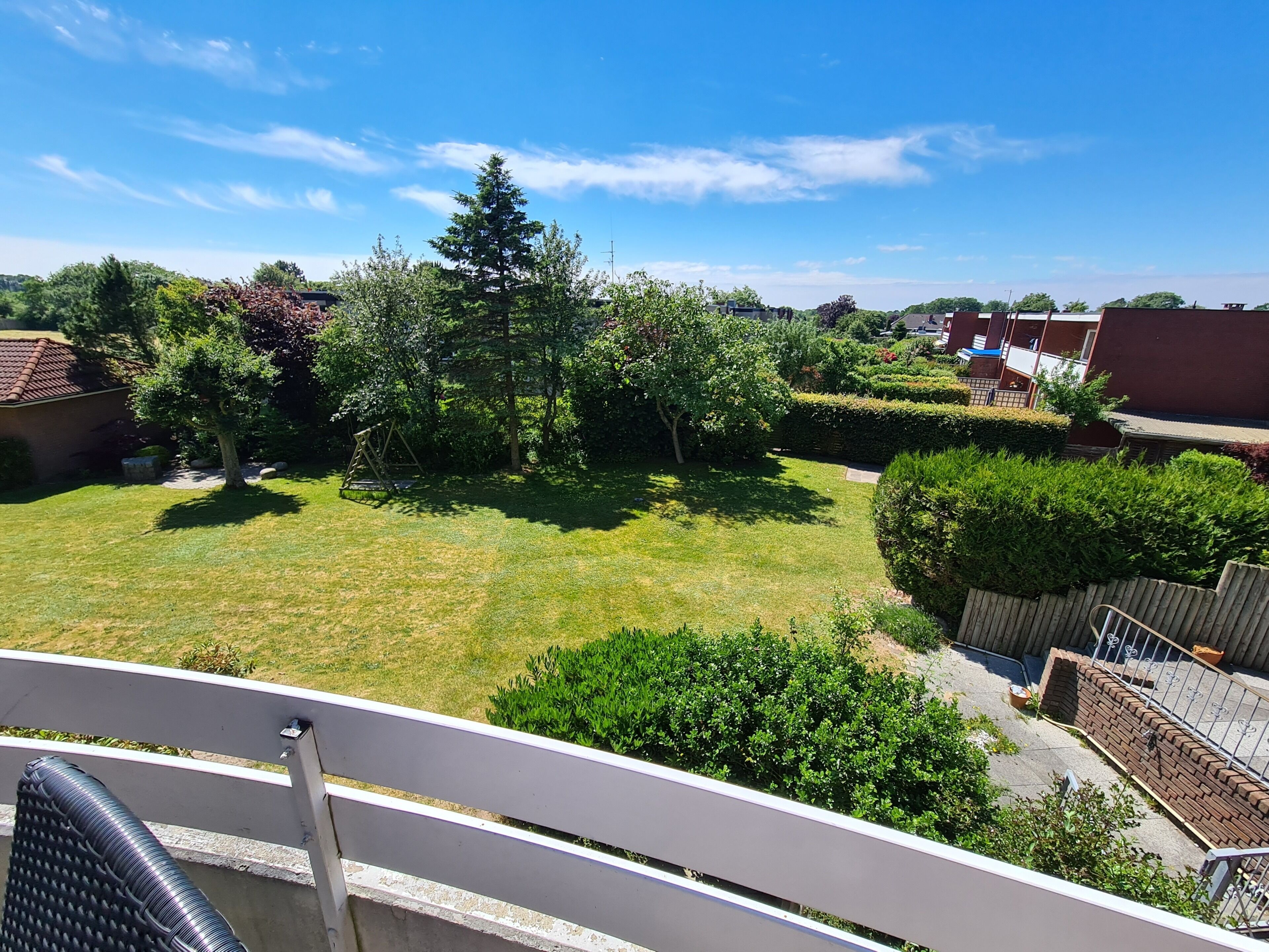 Ein Garten mit Rasen, Bäumen und einer Schaukel.