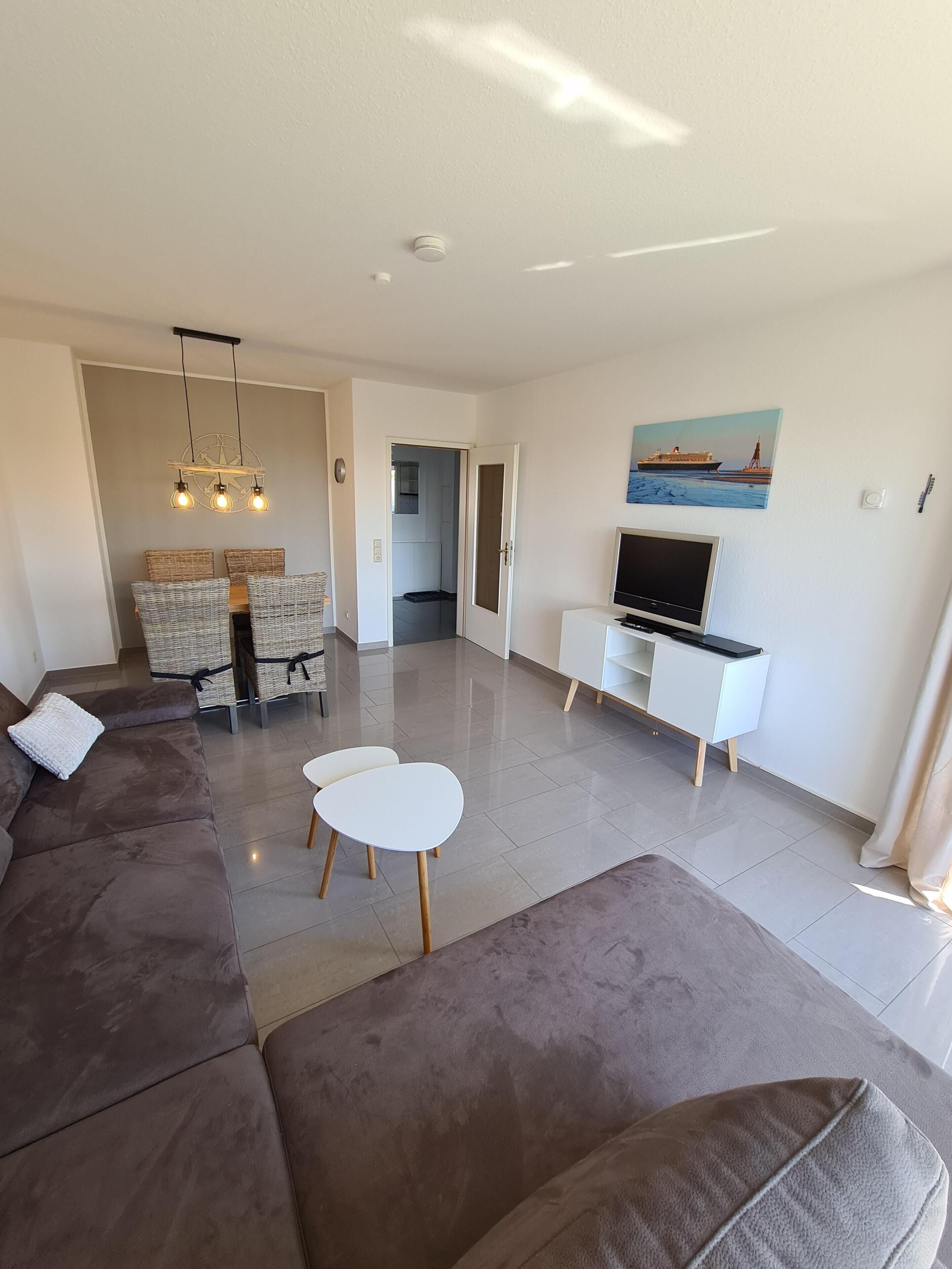 Ein modernes Wohnzimmer mit einem braunen Sofa, einem weißen Couchtisch und einem Fernsehschrank.