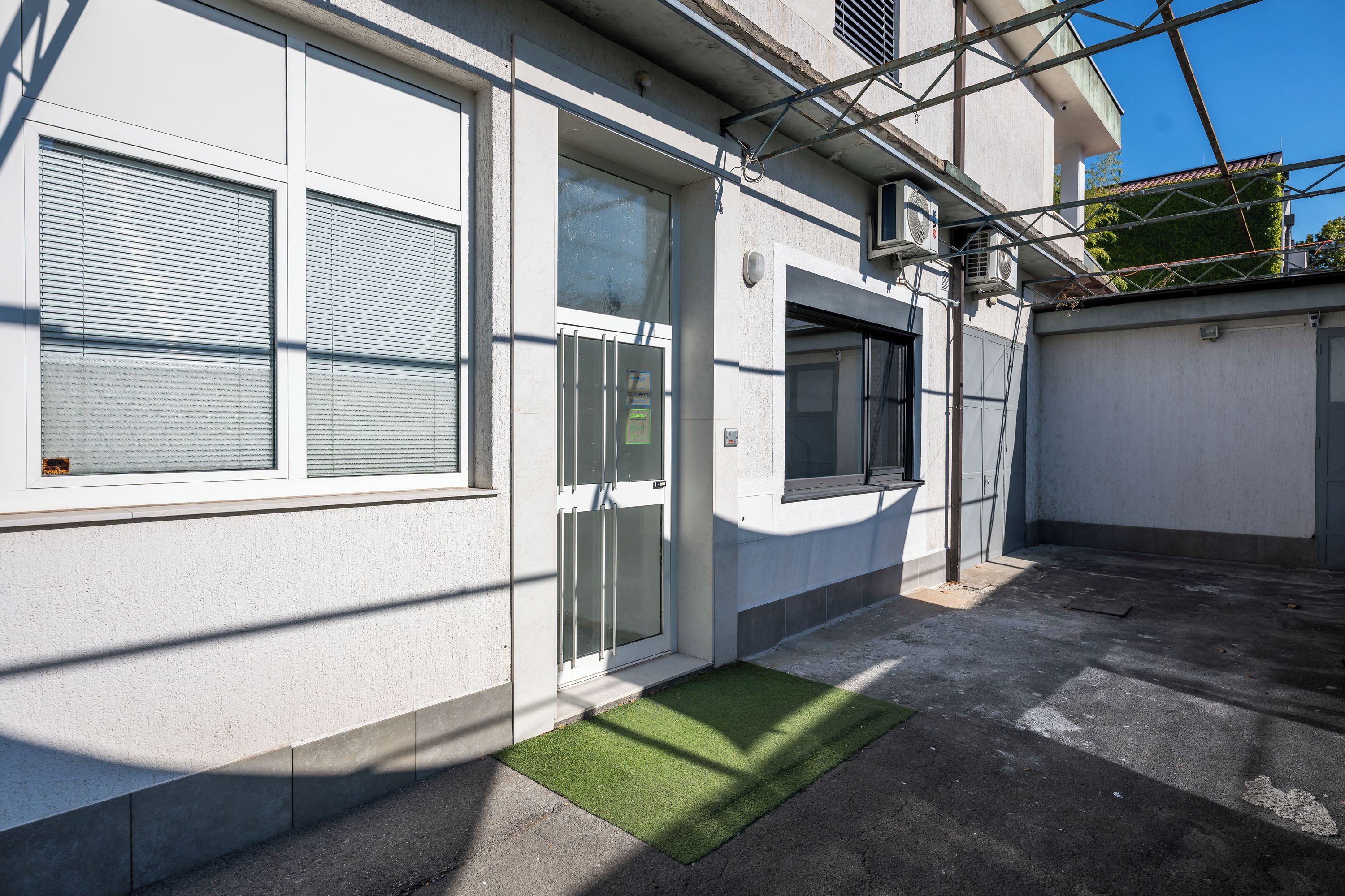Un bâtiment doté d’une porte de garage, d’une fenêtre avec des stores et d’un appareil de climatisation.