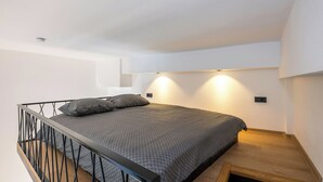 A bedroom with a bed, a wooden floor, a black metal railing, and a white ceiling. - Alter 26 Urban Apartment With Free Parking (Koper)