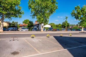 A parking lot with multiple parking spaces, some with yellow parking meters, and trees lining the area. - Alter 26 Urban Apartment With Free Parking (Koper)