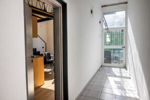 A hallway with a wooden floor, a door with a glass panel, and a staircase leading to a balcony. - Alter 26 Urban Apartment With Free Parking (Koper)