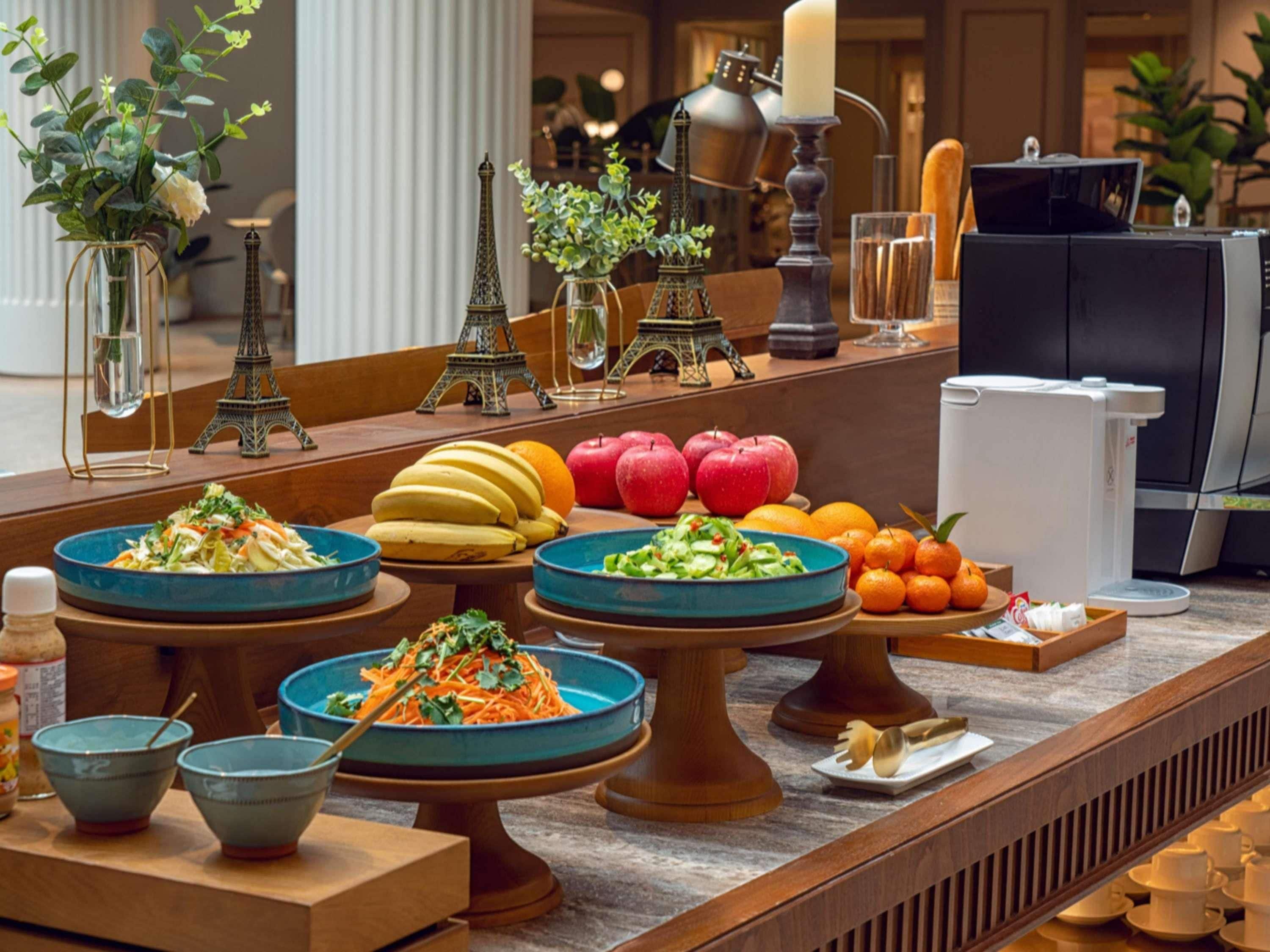 Un buffet proposant une variété de plats, notamment des salades, des fruits et une machine à café.
