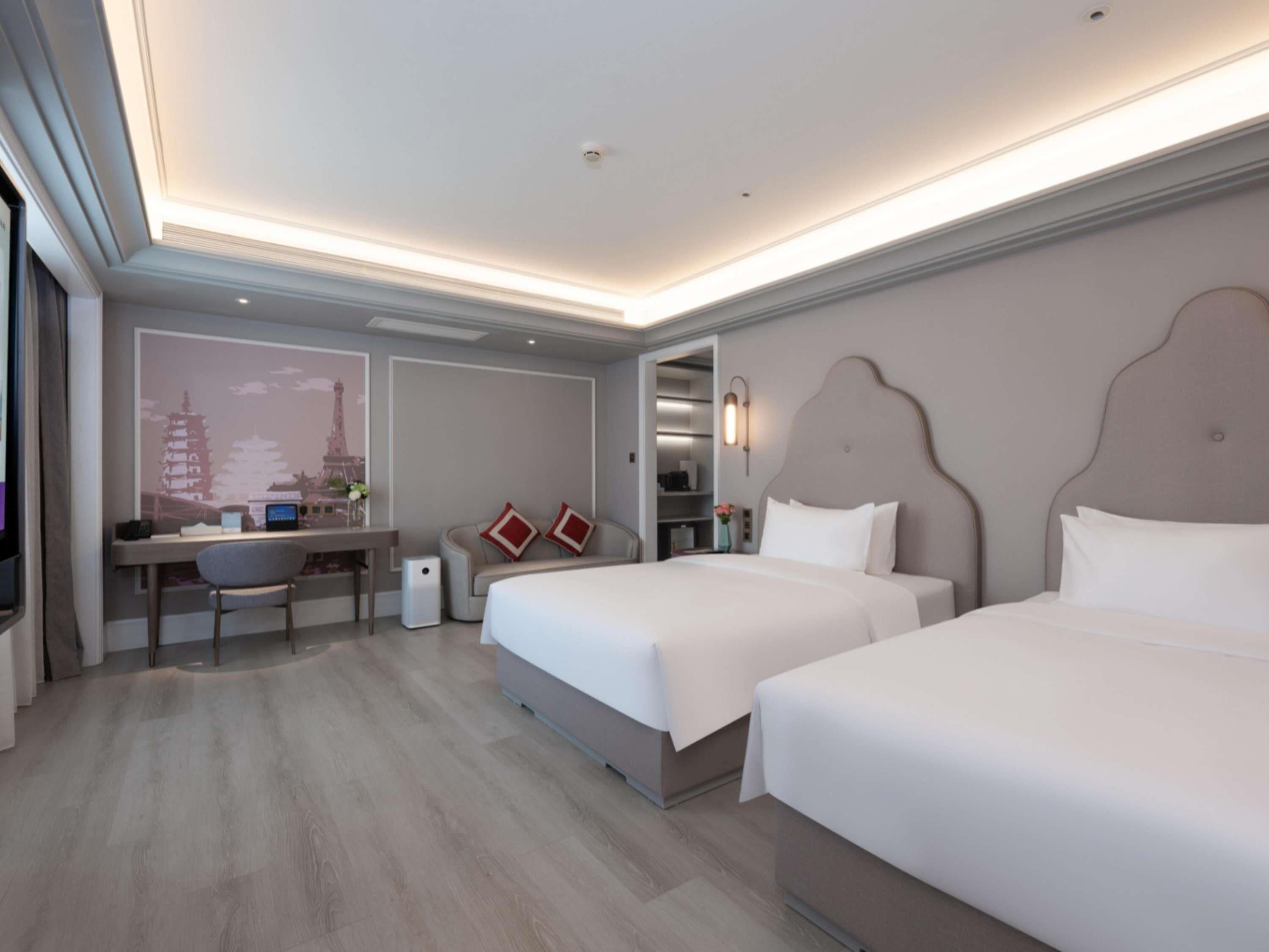 A hotel room with two beds, a desk, and a chair.