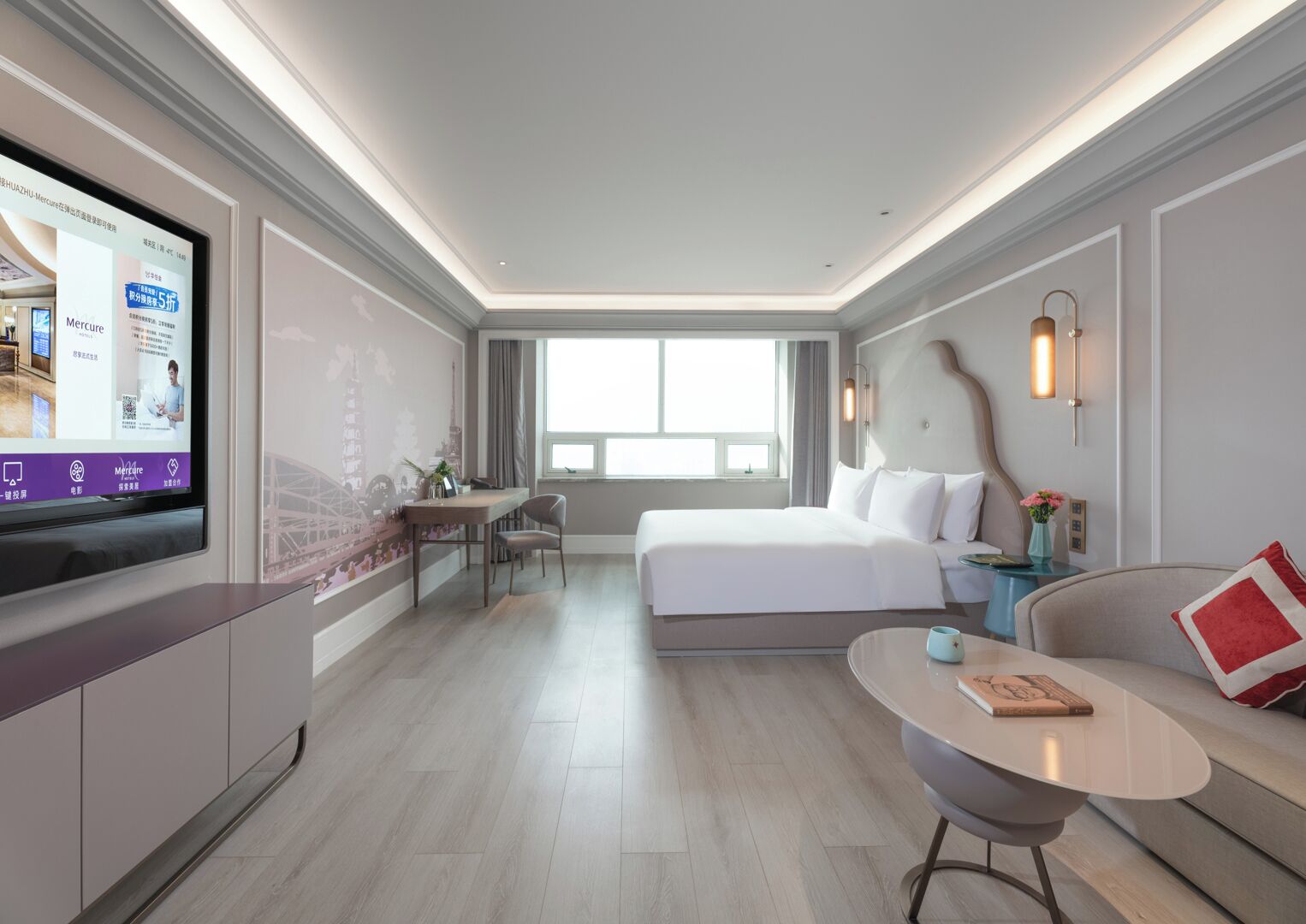 Et moderne hotelværelse med seng, skrivebord, fjernsyn og sofa.