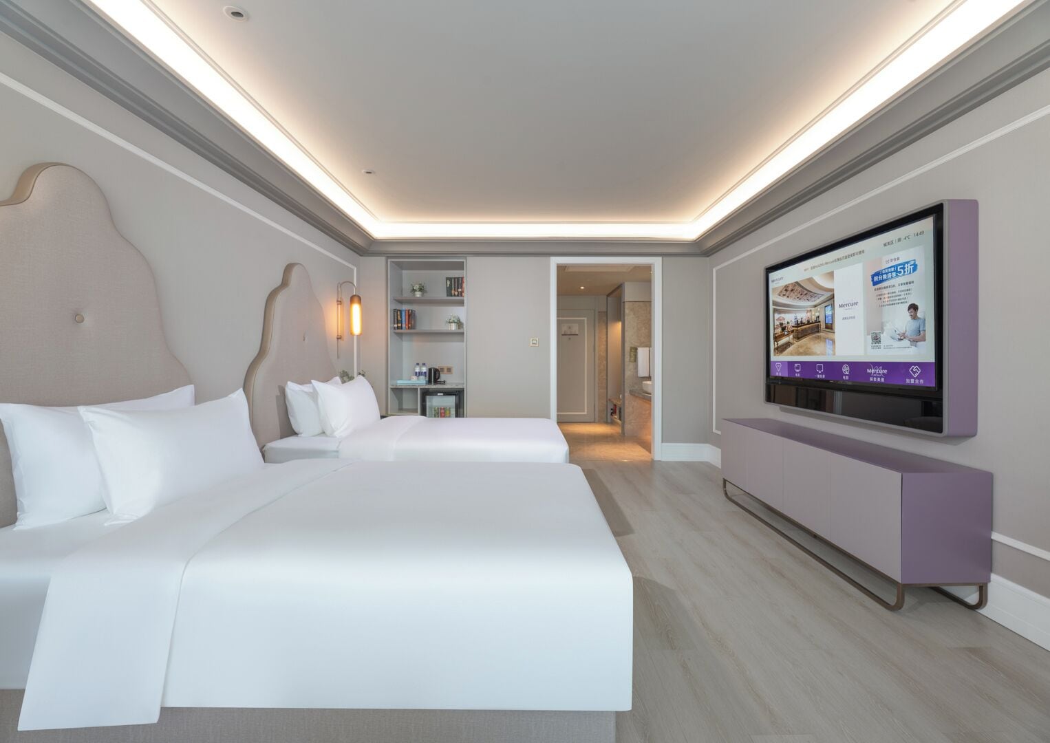 A hotel room with a large bed, a television mounted on the wall, and a small seating area with a table and chairs.
