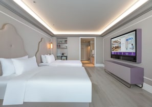 A hotel room with a large bed, a television mounted on the wall, and a small seating area with a table and chairs.