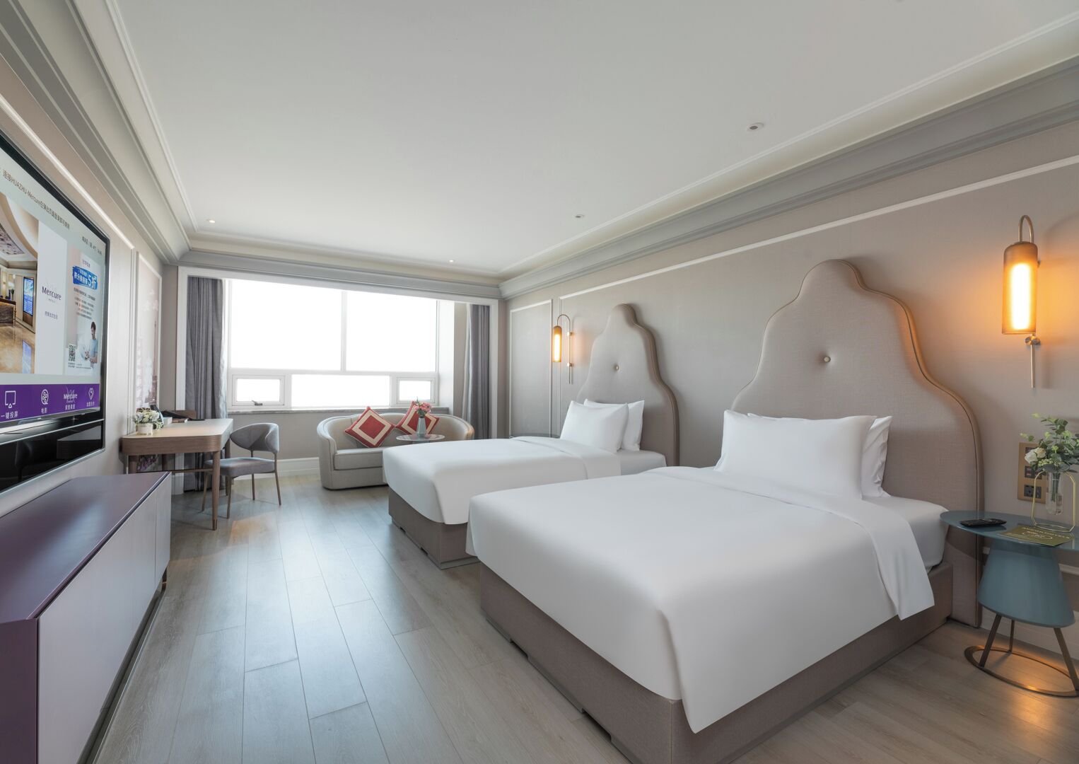 Habitación de hotel con dos camas, un escritorio, un sofá y un televisor.