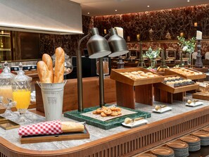 Montaje tipo buffet con diferentes opciones de comida, una estación de café y una Torre Eiffel decorativa.